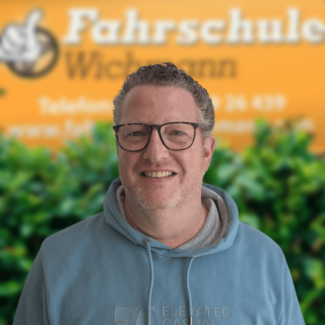 OliFahrlehrerFahrschuleWichmann Fahrschule Wichmann Ganderkesee Autoführerschein LKW Führerschein Motorradführerschein Fahrlehrer Torben von der Fahrschule Wichmann in Delmenhorst vor dem gelben Firmenschild